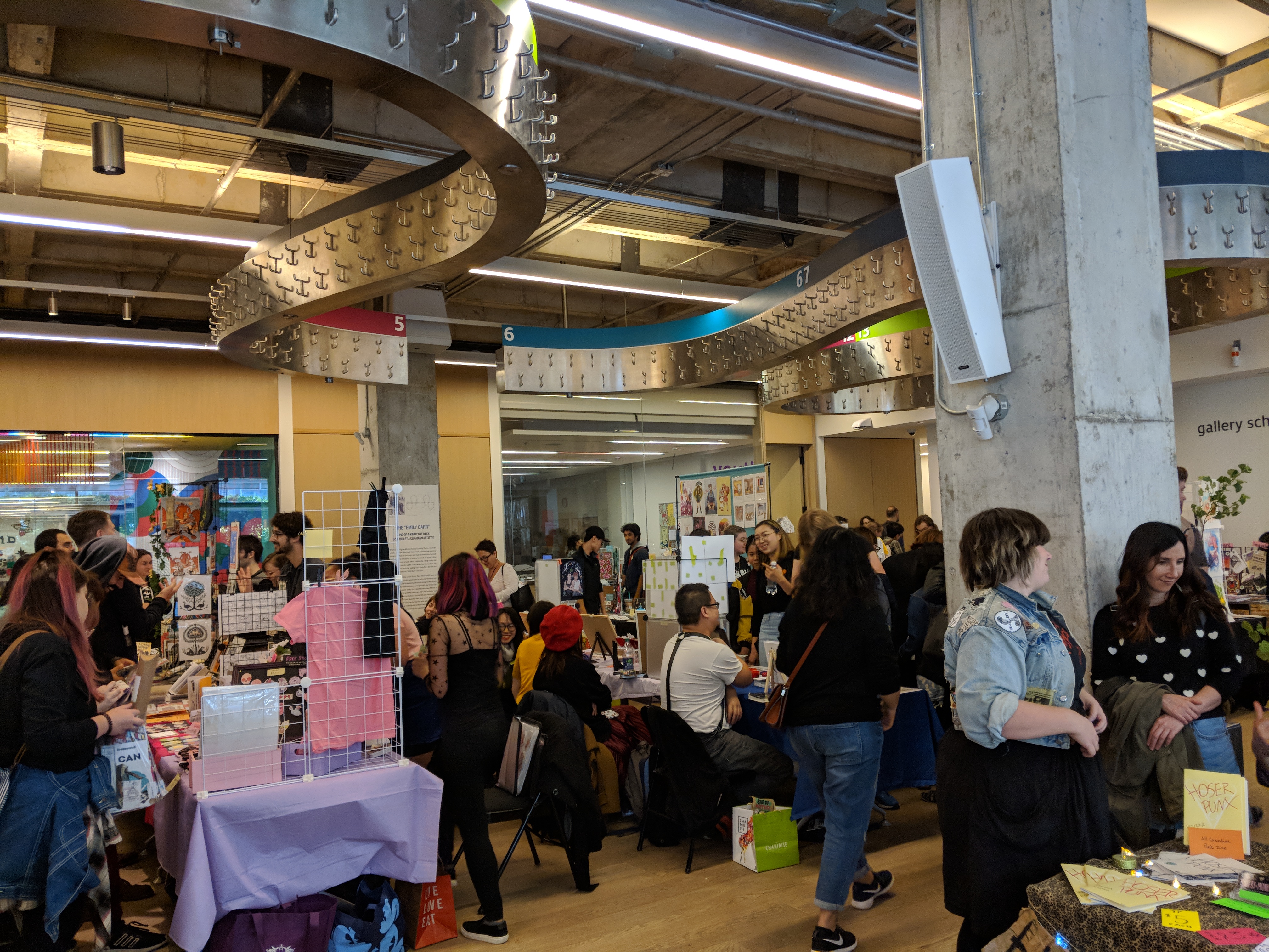 Photo of one of the rooms at the Art Gallery of Ontario full of tables covered in artwork, vendors and festival attendees.