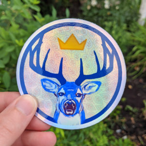 A round sticker with the face of a stag and his antlers frame a crown.